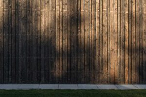 Detail dřevěného opláštění a plotu v tmavém odstínu ladícím s domem