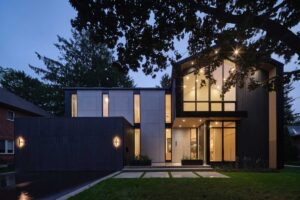 Exteriér moderního rodinného domu s velkými okny a večerním osvětlením