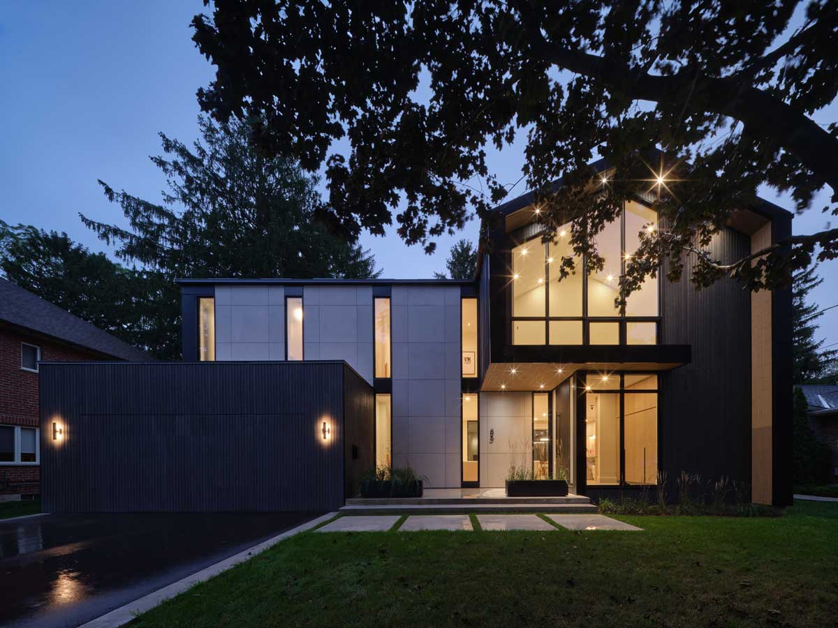 Exteriér moderního rodinného domu s velkými okny a večerním osvětlením