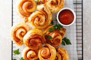 Upečené slané šneky z listového těsta s rajčatovou omáčkou na servírovacím roštu