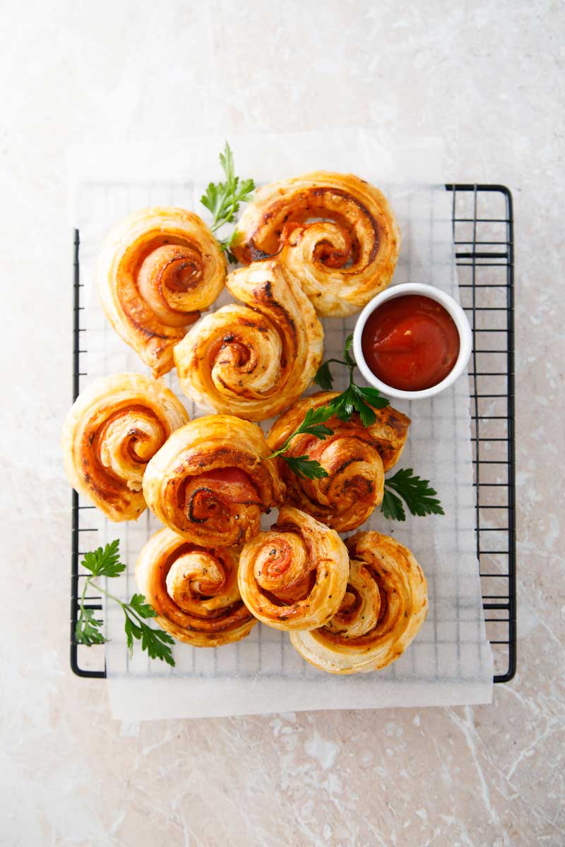 Upečené slané šneky z listového těsta s rajčatovou omáčkou na servírovacím roštu
