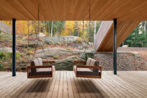 Krytá terasa s dřevěnou podlahou a závěsnými houpačkami mezi skalami