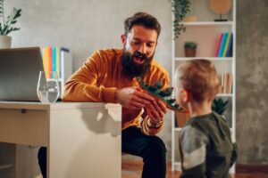 Tatínek si hraje s dítětem s dinosauří figurkou v obývacím pokoji