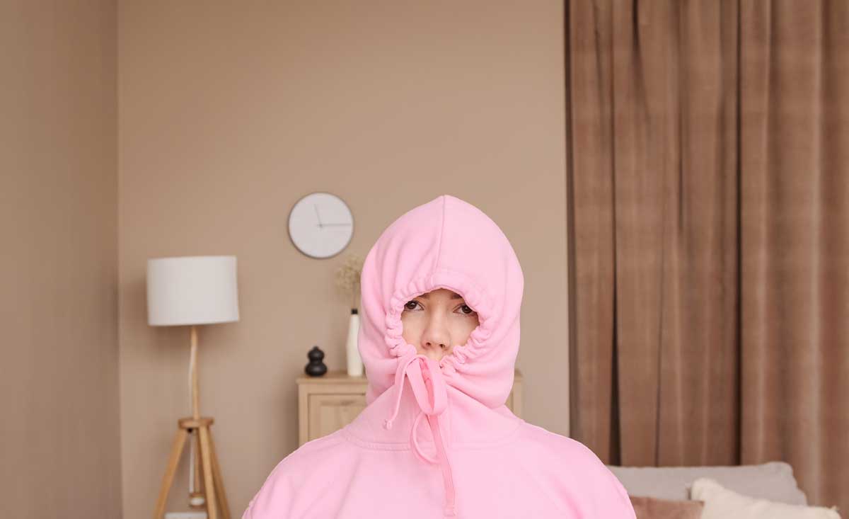 Žena schovaná v růžové mikině – symbol potřeby zimního klidu typického pro introverty.