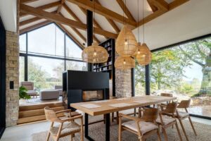 Jídelna s ratanovými lampami a výhledem na louky přes celostěnné prosklení