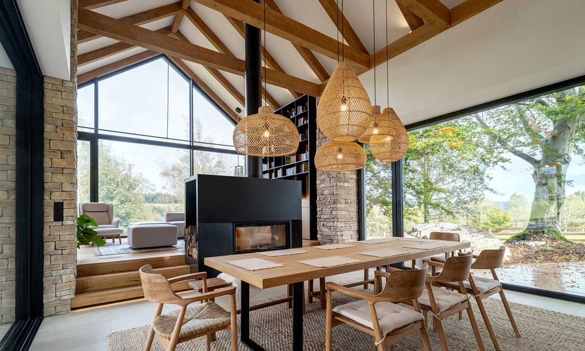 Jídelna s ratanovými lampami a výhledem na louky přes celostěnné prosklení