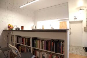 Jídelní pult s pracovní deskou a bílou knihovnou v podstavci.