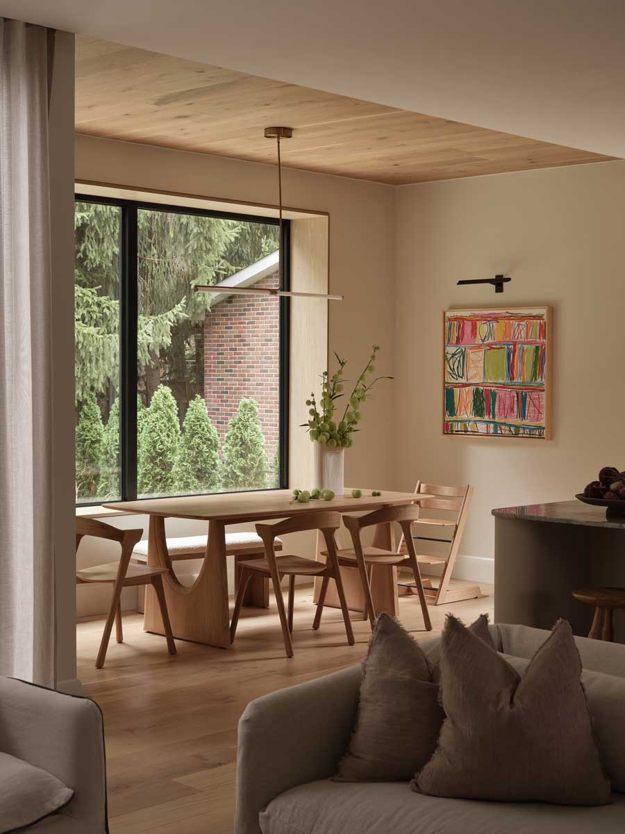 Dřevěný jídelní stůl u velkého okna s výhledem do zahrady