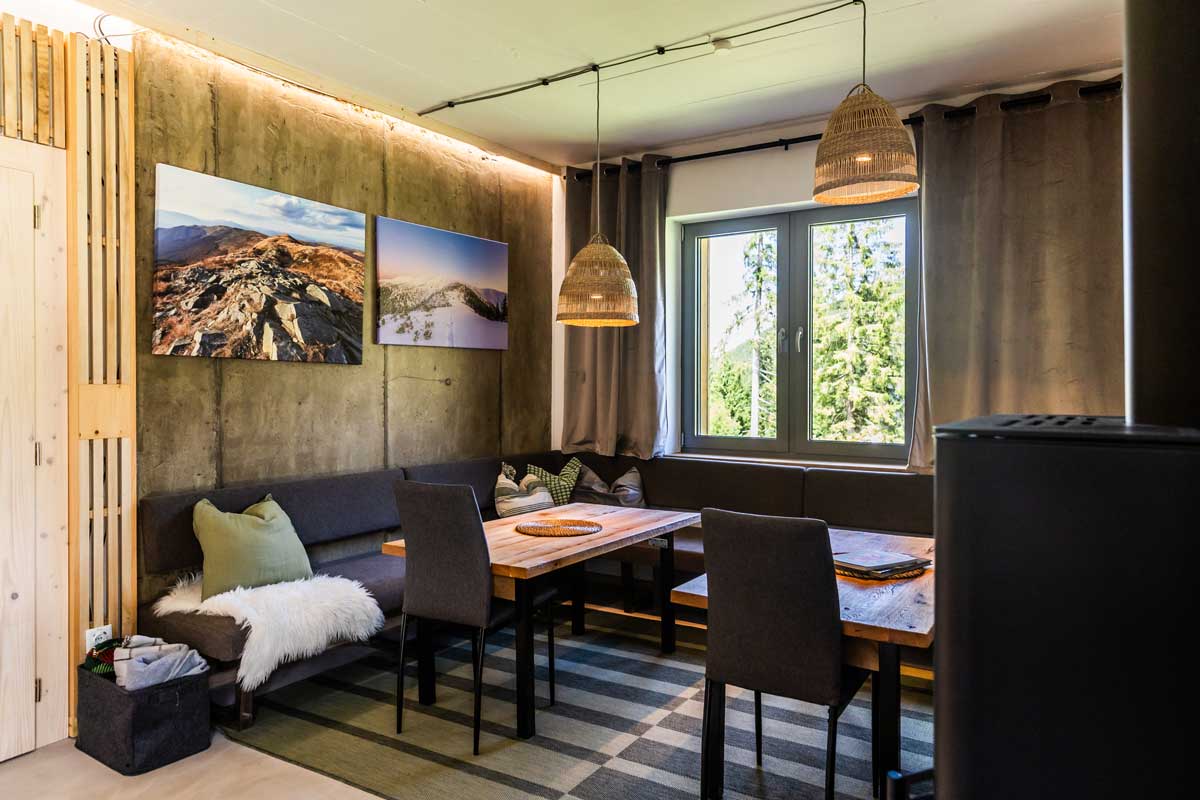 Jídelní kout v horské chatě s dřevěným stolem, lavicí a výhledem do krajiny