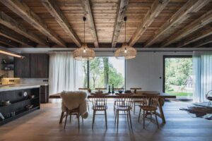 Jídelní stůl pod trámovým stropem v moderní horské chalupě