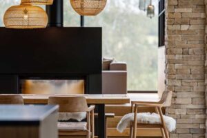 Jídelní kout s krbem, přírodním dřevem a kamennými prvky v moderním horském domě