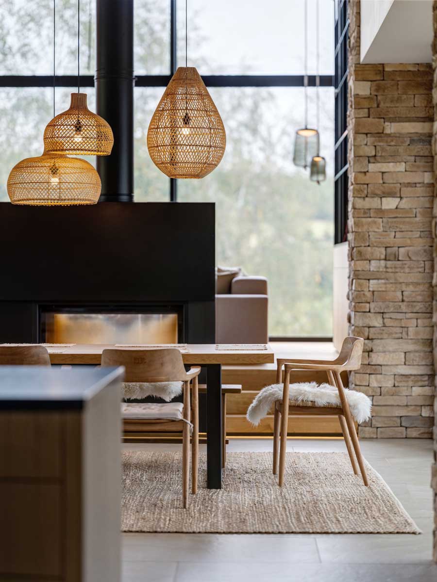 Jídelní kout s krbem, přírodním dřevem a kamennými prvky v moderním horském domě