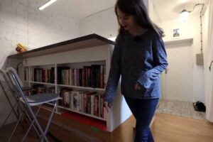 Vestavěná knihovna pod jídelní pracovní deskou v garsonce.