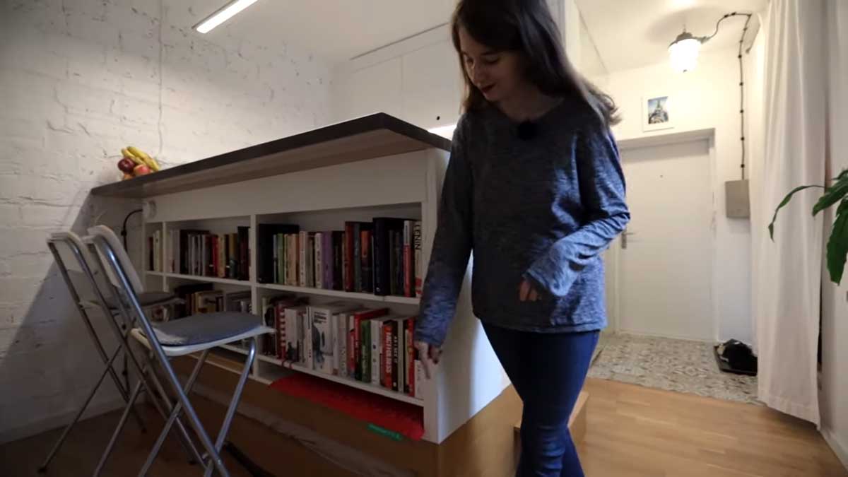 Vestavěná knihovna pod jídelní pracovní deskou v garsonce.