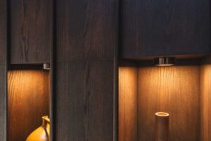 Detail truhlářských skříní s dekoracemi a jemným osvětlením v horské chalupě