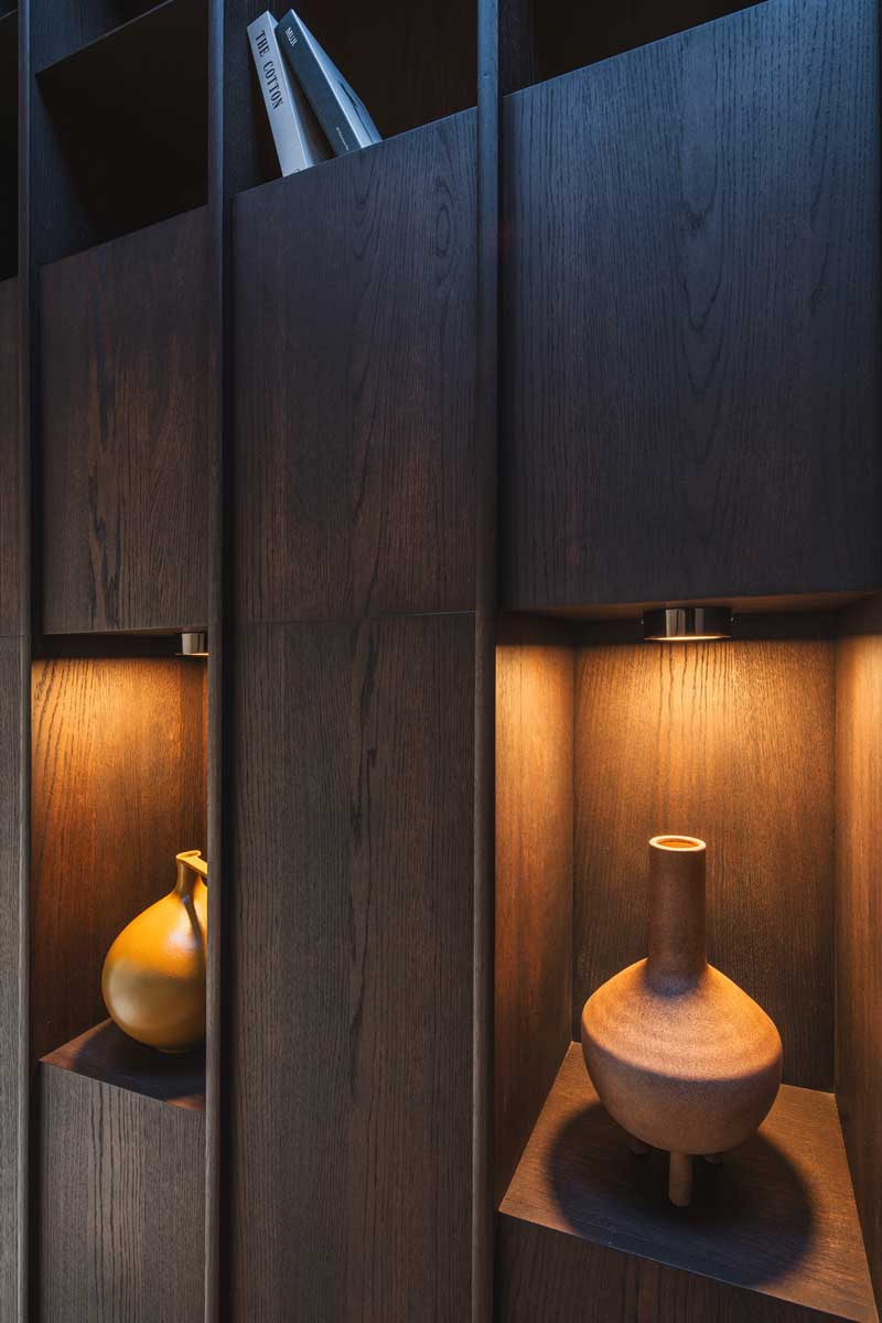 Detail truhlářských skříní s dekoracemi a jemným osvětlením v horské chalupě