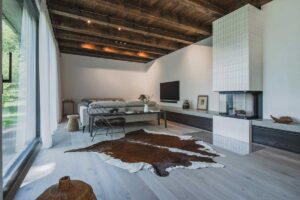 Obývací část s krbem, gaučem a kožešinovým kobercem v moderní chalupě