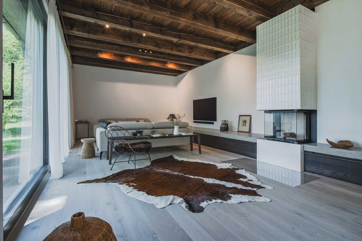 Obývací část s krbem, gaučem a kožešinovým kobercem v moderní chalupě