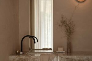 Detail černého kuchyňského kohoutku nad mramorovou deskou v minimalistickém interiéru