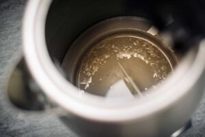 Detail vnitřku rychlovarné konvice s viditelnými usazeninami vodního kamene, které se v zimě tvoří rychleji kvůli teplejší vodě.