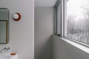 Minimalistická koupelna otevírá intimní pohled do zimní krajiny a zdůrazňuje klid celého domu.