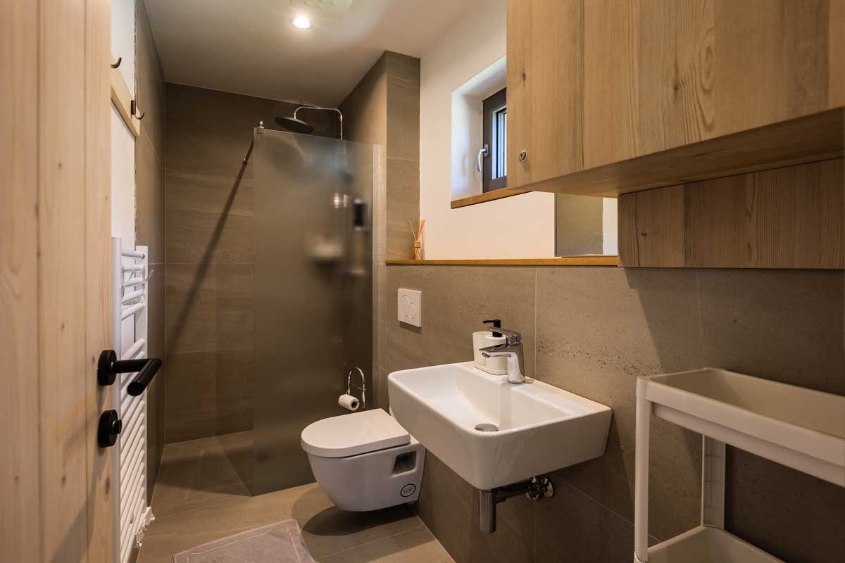 Moderní koupelna v horské chatě se sprchovým koutem, betonovým obkladem a dřevem