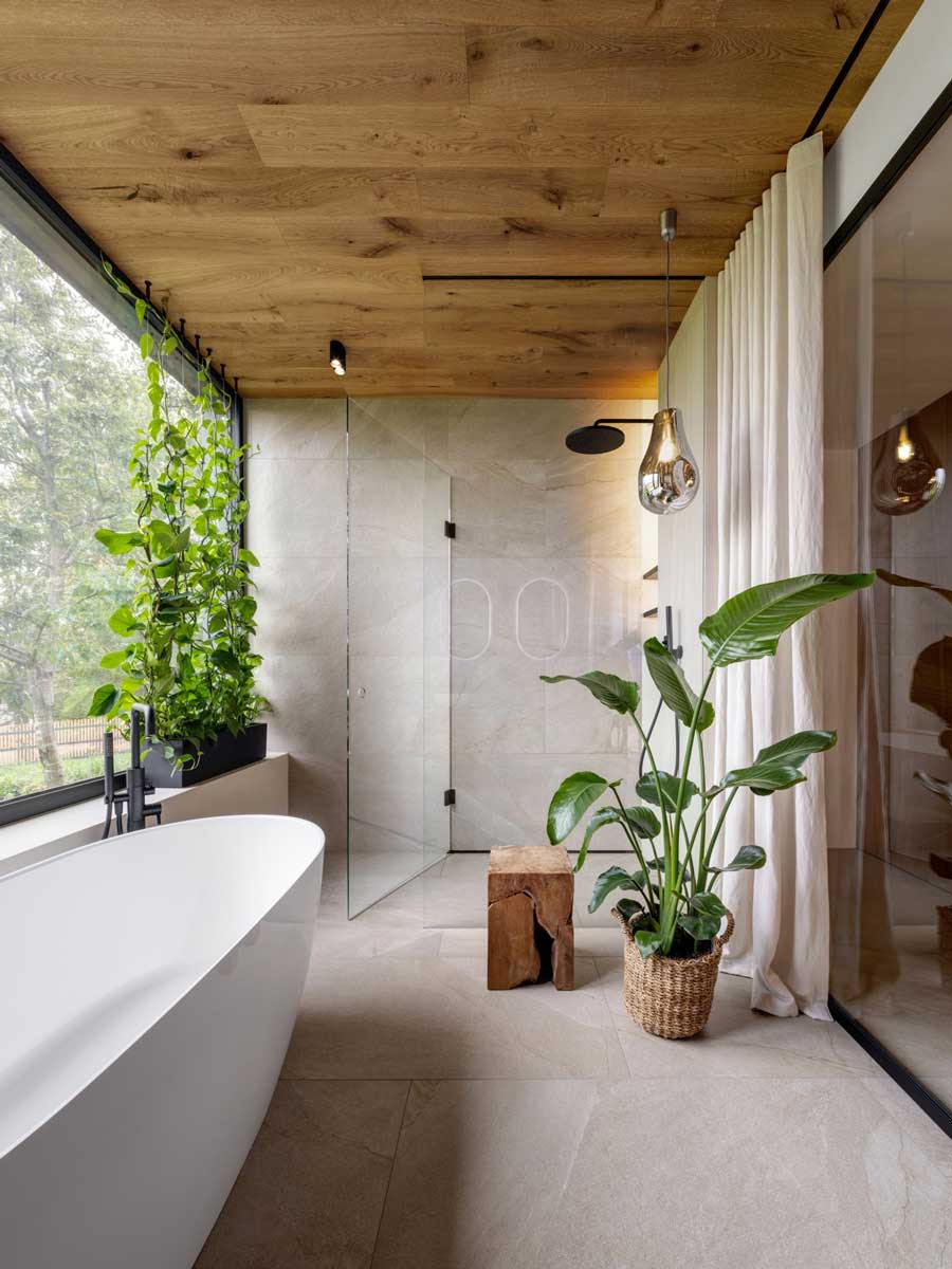 Designová koupelna s volně stojící vanou, sprchovým koutem a velkým oknem s rostlinami