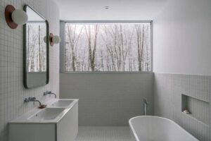 Volně stojící vana zve k odpočinku a rámuje zasněžený les jako živý obraz.