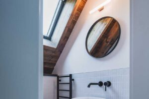 Dvojité umyvadlo s kruhovými zrcadly a dřevěným nábytkem v koupelně chalupy