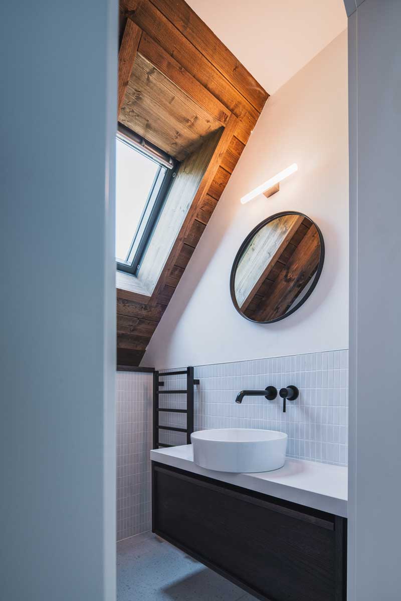 Dvojité umyvadlo s kruhovými zrcadly a dřevěným nábytkem v koupelně chalupy