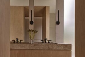 Umyvadlová skříň z přírodního dřeva s kamennou deskou a zrcadly v koupelně