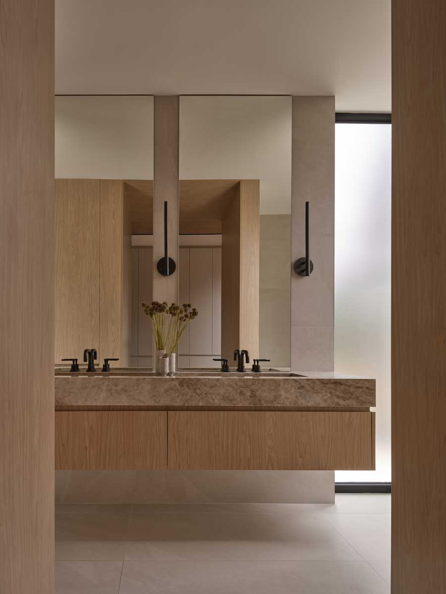 Umyvadlová skříň z přírodního dřeva s kamennou deskou a zrcadly v koupelně