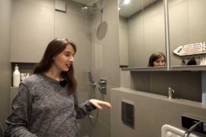 Moderní šedá koupelna v garsonce s vestavnými úložnými díly a sprchovým koutem.