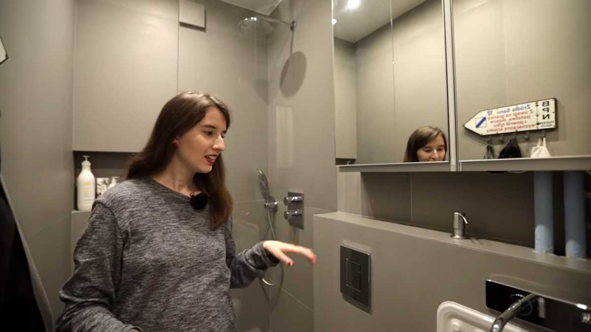 Moderní šedá koupelna v garsonce s vestavnými úložnými díly a sprchovým koutem.