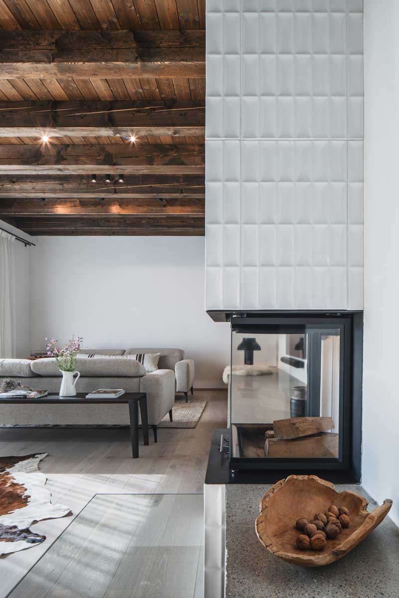 Kachlová kamna s bílým keramickým obkladem a dřevěnými trámy nad nimi