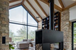 Obytný prostor s dominantním krbem, dřevěnými stropy a velkým prosklením.