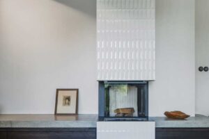 Křeslo u krbu v obývacím pokoji horské chalupy s kachlovými kamny a dřevěným stropem