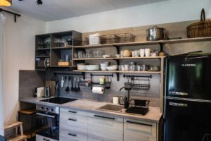 Plně vybavená kuchyně v horské chatě s otevřenými policemi a dřevěnou pracovní deskou