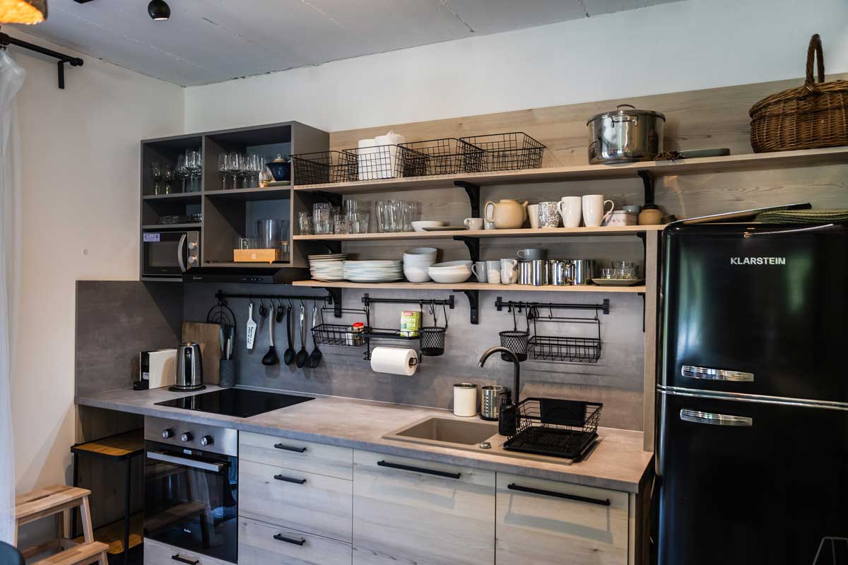 Plně vybavená kuchyně v horské chatě s otevřenými policemi a dřevěnou pracovní deskou