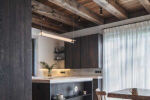 Otevřený prostor kuchyně a jídelny s velkým stolem a dřevěnými trámy