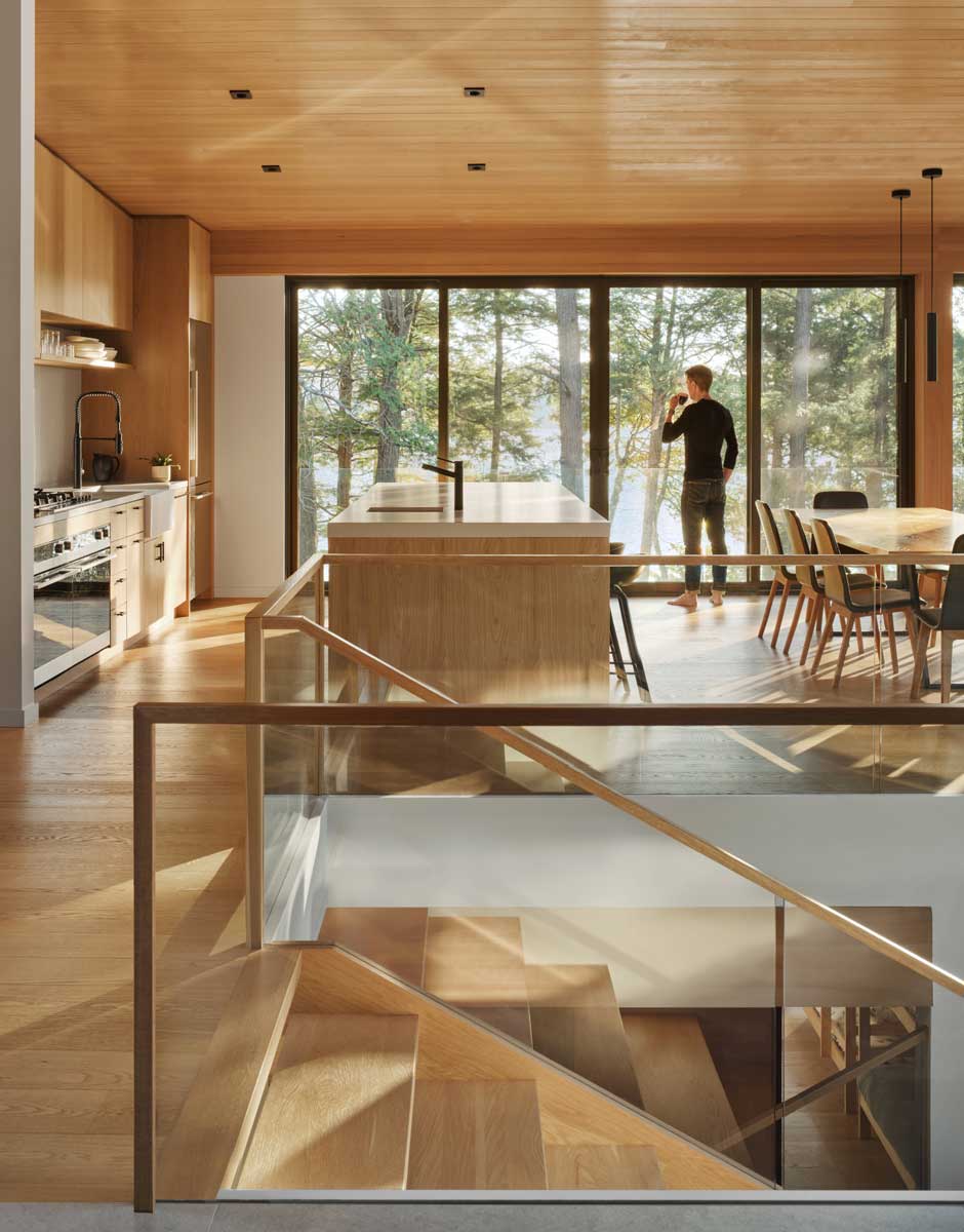 Otevřený prostor kuchyně a jídelny s dřevěným stropem a velkými okny