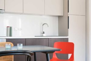 Jídelní stůl s mixem židlí v interiéru zdobeném moderním uměním a barevnými doplňky.