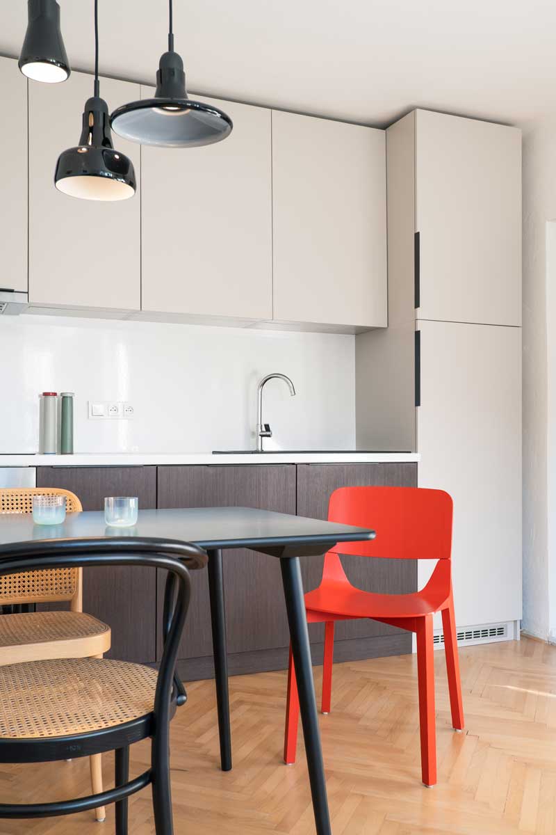 Jídelní stůl s mixem židlí v interiéru zdobeném moderním uměním a barevnými doplňky.