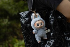 Přívěsek Labubu zavěšený na elegantní černé kabelce s geometrickým vzorem.