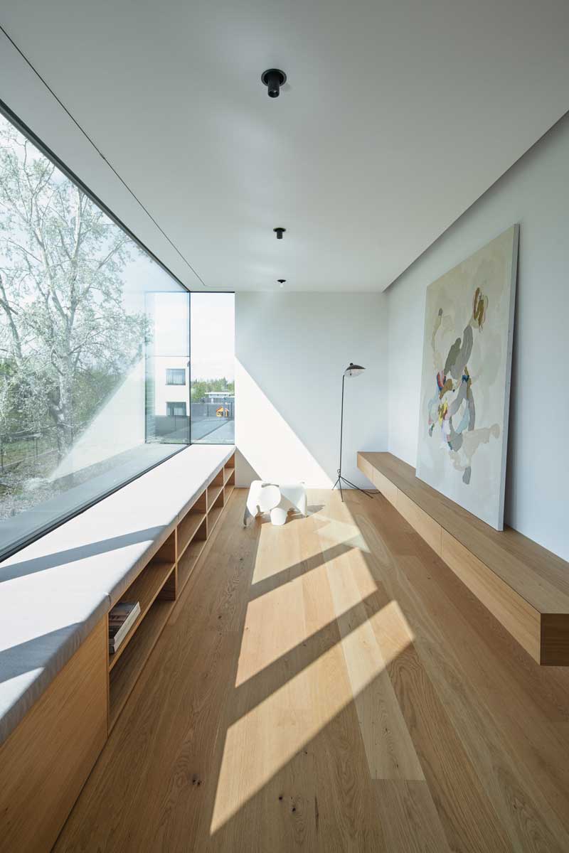 Světlem zalitý kout s dlouhou vestavěnou lavicí u panoramatického okna s výhledem do okolí.