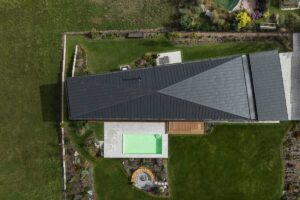 Letecký pohled na dům ve tvaru písmene I se zapuštěným bazénem a terasami