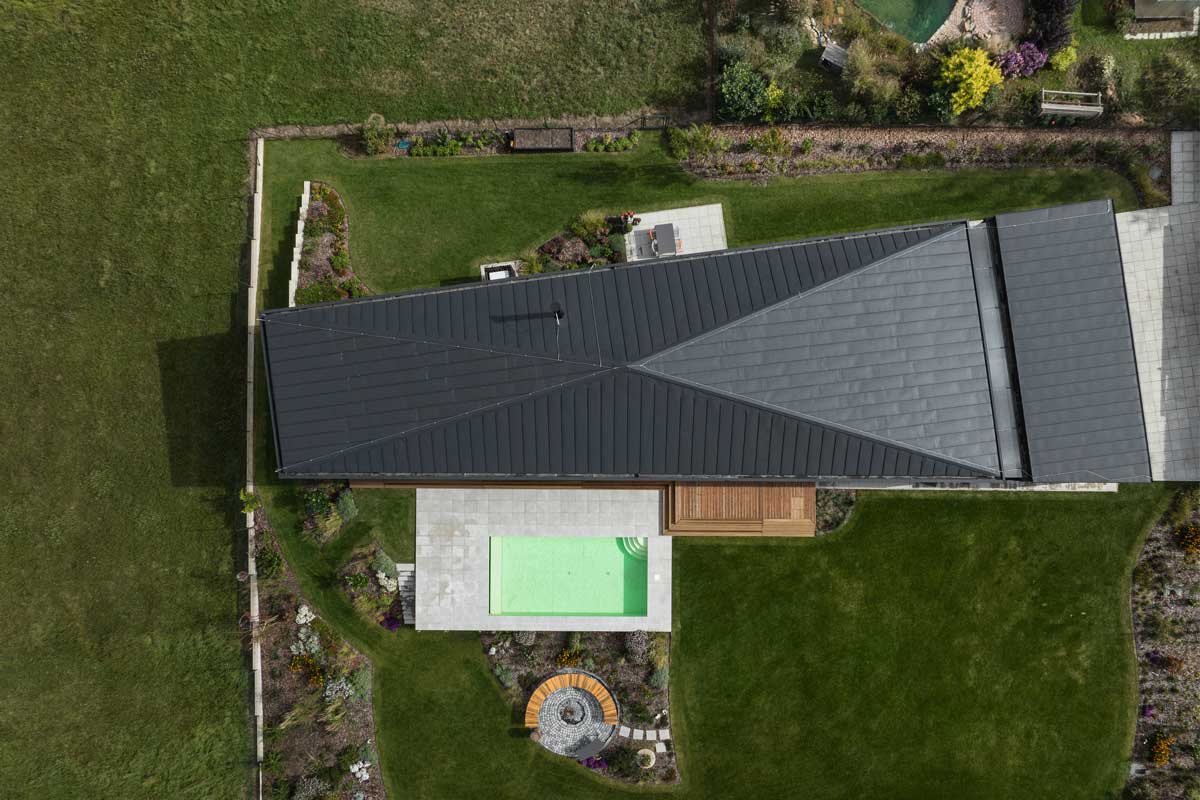 Letecký pohled na dům ve tvaru písmene I se zapuštěným bazénem a terasami