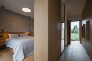 Minimalistická ložnice s dubovou podlahou vestavěným nábytkem a jemným osvětlením.