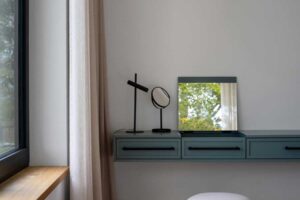 Minimalistický toaletní koutek s designovými zrcadly a pudrovým taburetem v moderní ložnici.