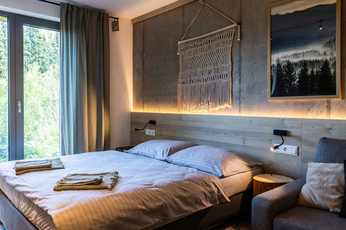 Minimalistická ložnice v horské chatě s betonovými stěnami, dřevem a přirozeným světlem
